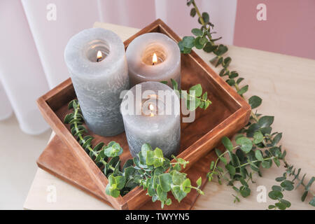 Scatola con candele accese e rami di eucalipto su tavola Foto Stock