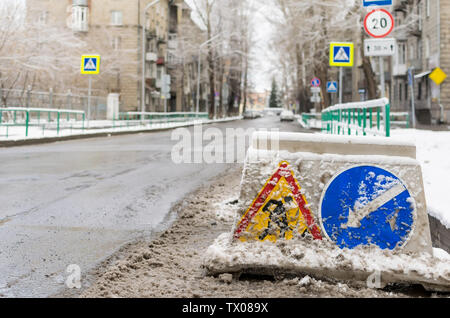 segnaletica stradale spazzata dalla neve, riparazione stradale, si trova sulla strada della strada della città Foto Stock