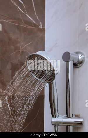 L'acqua che scorre dalla testa di doccia e rubinetto in una moderna stanza da bagno doccia fresca con gocce d'acqua schizzi. Foto Stock