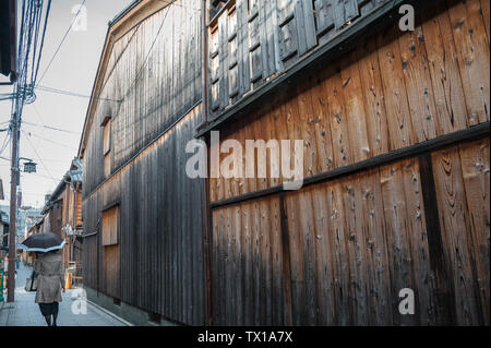 Edo tradizionale architettura di stile nel quartiere di Gion. Donna con ombrello passeggiate lungo la stradina allineata con costruzioni in legno Foto Stock