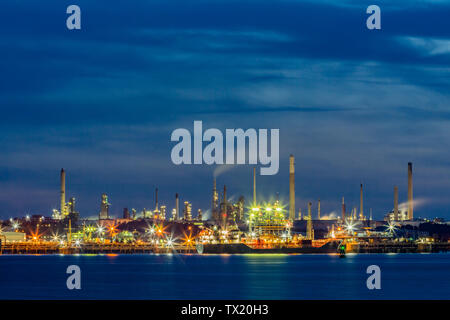 Fawley raffineria di petrolio su Southampton acqua durante le ore di colore blu Foto Stock