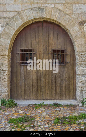 Vecchio arcuata porta in legno con finestre sbarrate. Foto Stock