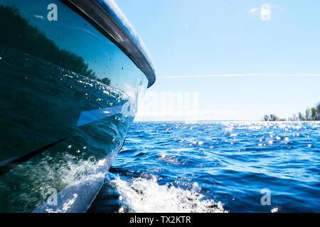 Vista laterale velocizzando la pesca con una barca a motore con gocce di acqua. Oceano Blu acqua di mare riflessioni d'onda con fast yacht di pesca. Imbarcazione a motore in blu oceano Foto Stock