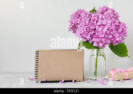 Bigliettino vuoto di rosa fiori di ortensie e confezione regalo su sfondo bianco. moderna ancora in vita. sfondo di nozze Foto Stock