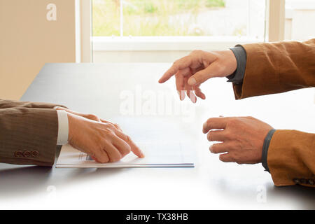 Le mani da due imprenditori in conversazione da una scrivania. Uno rivolto a carte. Attività di negoziazione o di un colloquio di lavoro. - Immagine Foto Stock