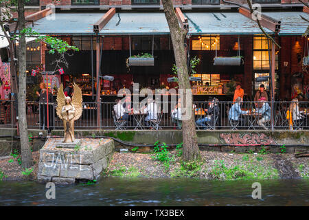 Oslo cafe bar, vista dei giovani seduti sulla terrazza sul fiume di Bla - un popolare bar/club in alternativa Grünerløkka nel centro di Oslo, Norvegia Foto Stock