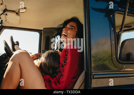 Allegro giovane seduto in loro automobile godendo il viaggio su strada. Uomo disteso su di giri della sua donna seduta in auto. Foto Stock