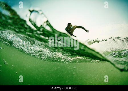 Surfista maschio rendendo cutback da dietro onda oceano Foto Stock