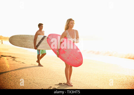 Coppia giovane con tavole da surf camminando sulla spiaggia Sunny Beach Foto Stock