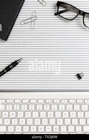 Vista da sopra la tastiera del computer, penna e occhiali sulla scrivania Foto Stock
