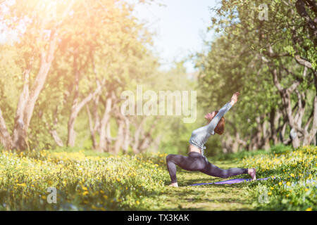 Foto di donna con le braccia sollevate a praticare yoga nei boschi durante il giorno Foto Stock