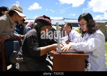 (190624) -- MAQU, Giugno 24, 2019 (Xinhua) -- aiuto medico membro del team Xin Qin(R) misura la pressione del sangue per un residente locale in Maqu contea di Gannan tibetano prefettura autonoma, a nord-ovest della Cina di Provincia di Gansu, il 23 giugno 2019. Gansu secondo provinciale del popolo ospedale ha inviato oltre 30 medici in quattro lotti per fornire aiuto medico nella contea di Maqu sin dalla fine del 2015. I medici ha superato le difficoltà di malessere da altitudine e scomodo il trasporto durante il trattamento di pazienti sui prati dell'altopiano. Aver servito quasi 10 000 persone finora, il team medico ha risolto i pastori' Foto Stock