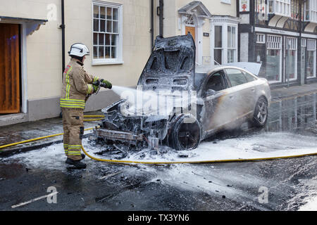 Un membro della metà e West Wales Fire e servizio di soccorso estinzione di un incendio auto in Presteigne, Powys, Wales, Regno Unito Foto Stock