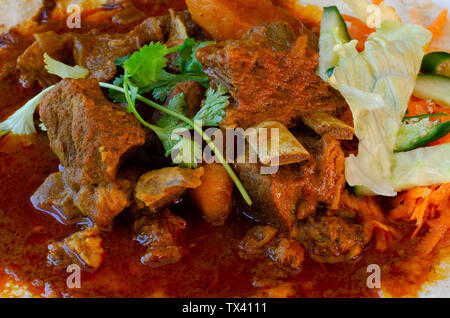 Un curry di montone roti con sambals - un iconico Durban pasto composto da un roti condito con curry di montone e sugo di carne. Il sambals sono carote grattugiate con c Foto Stock