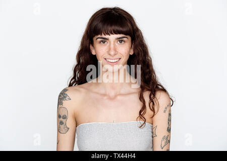 Ritratto di sorridente giovane donna con le lentiggini e tatuaggi sui suoi bracci superiori Foto Stock