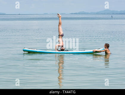 Thailandia, Krabi, Lao Liang, donna facendo un headstand sul SUP Board nell'oceano Foto Stock