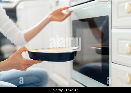 Close-up di donna mettendo torte nel forno Foto Stock