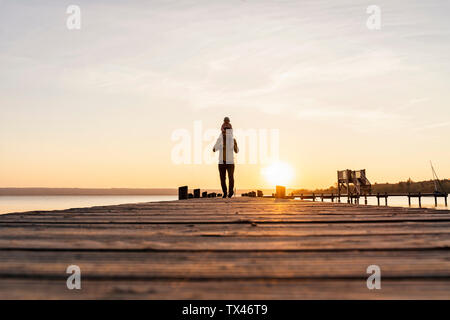 In Germania, in Baviera, Herrsching, padre figlia che porta sulle spalle sul molo al tramonto Foto Stock