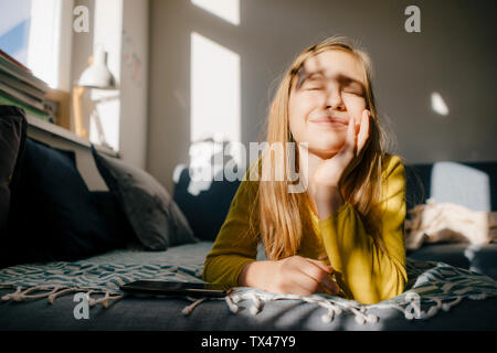 Ragazza distesa sul lettino a casa nella luce del sole Foto Stock