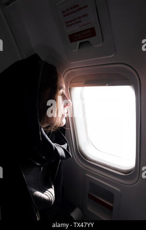 Profilo di donna in aereo guardando fuori della finestra Foto Stock