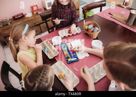 I bambini di pittura delle uova di Pasqua sulla tavola a casa Foto Stock