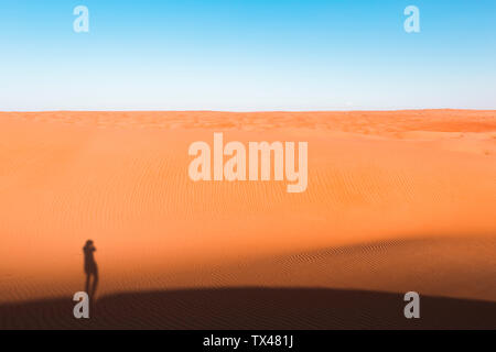 Ombra di un uomo in piedi nel deserto, Wahiba Sands, Oman Foto Stock