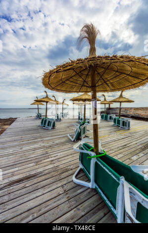 Mallorca, Colonia de Sant Jordi, terrazza in legno con ombrelloni di paglia e lettini per prendere il sole Foto Stock