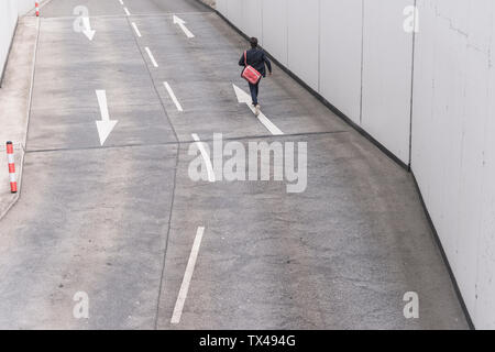 Vista posteriore di imprenditore in esecuzione su strada con freccia segni Foto Stock