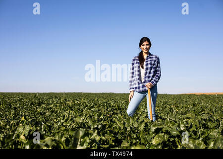 Donna giovane agricoltore con la zappa sul campo Foto Stock