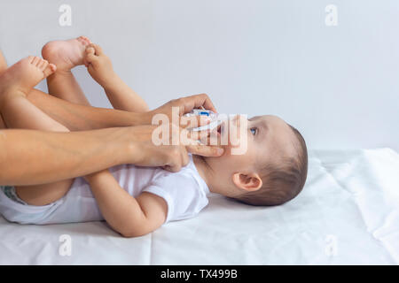 Madre messo gocce di soluzione salina nel neonato al naso. Little Boy getting gocce nasali. 6-mese baby boy riceve gocce nasali. Pediatra mettendo gocce di soluzione salina in infan Foto Stock