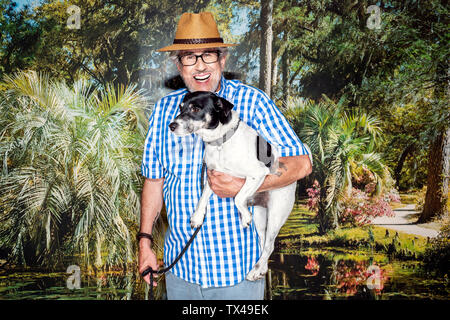 Senior uomo con un cappello e un cane, in piedi di fronte a uno sfondo di foto Foto Stock