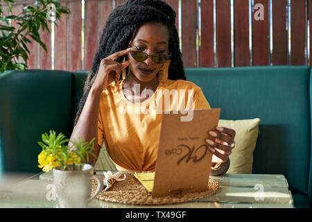 Giovane donna con dreadlocks controllando il menu in un cafe Foto Stock