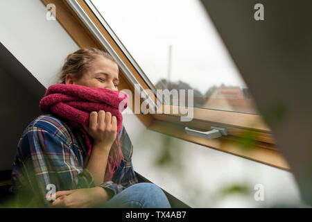 Felice giovane donna con sciarpa in corrispondenza della finestra Foto Stock