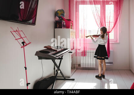 Ragazza suona il violino presso la finestra a casa Foto Stock