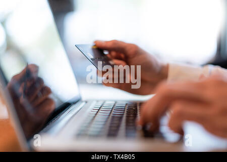 Uomo di mani tenendo la carta di credito e la digitazione su computer, close-up Foto Stock