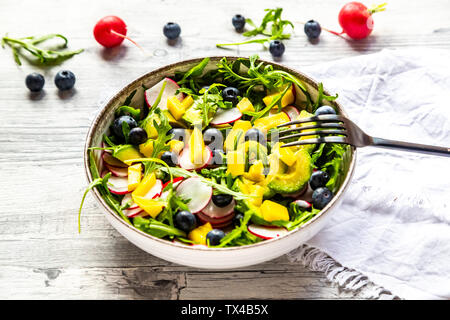 Ciotola di insalata di rucola con mango, avocado, rosso ravanelli e mirtilli Foto Stock