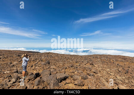 Stati Uniti d'America, Hawaii, Mauna Kea vulcano, femmina turistica prendendo una foto del paesaggio vulcanico Foto Stock