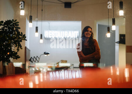 Donna sorridente indossando il grembiule in piedi in un ristorante Foto Stock