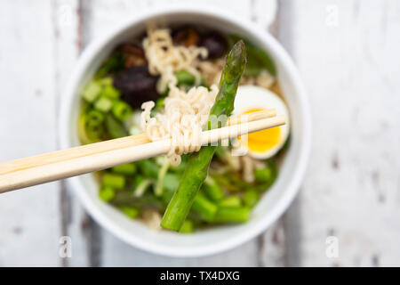 Ciotola di zuppa di ramen con uovo, asparagi verdi, tagliatelle, Funghi Shitake e cipolline Foto Stock