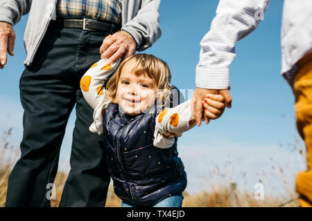Ritratto di felice bambina passeggiando con il nonno e fratello mano nella mano in natura Foto Stock
