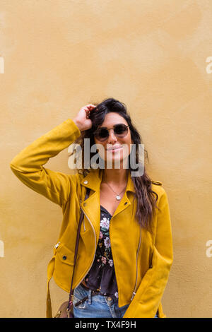 Ritratto di giovane donna che indossa il giallo giacca di pelle e occhiali da sole Foto Stock