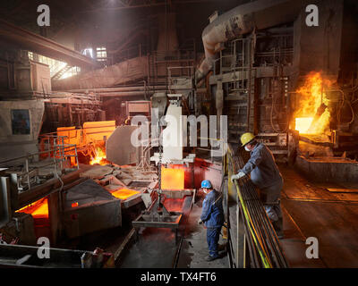 Industria, lavoratore di sollevamento delle piastre di rame con la gru interna per il raffreddamento nel bacino di acqua Foto Stock