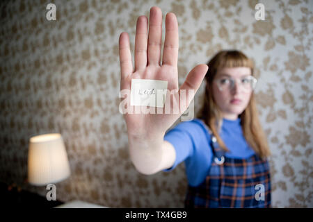 Lo studente che mostra il suo lato, una nota con la parola soffrire sulla sua mano Foto Stock