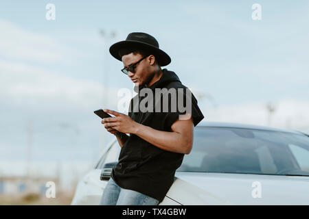 Ritratto di un giovane uomo di invio di un messaggio di posta elettronica con il telefono Foto Stock