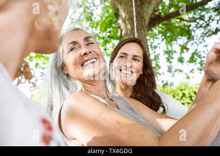 Le donne di una famiglia relax nel giardino, seduto su un letto di oscillazione Foto Stock