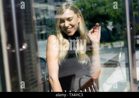 Ritratto di ridere giovane donna dietro il vetro di finestra Foto Stock