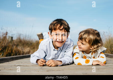 Ritratto di ragazzo e la sua sorellina affiancati sul Boardwalk divertendosi Foto Stock