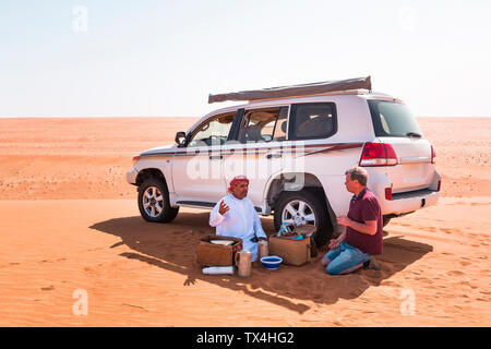 Tourist avente una pausa caffè con il suo driver locale nel deserto Wahiba Sands, Oman Foto Stock