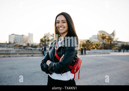 Felice giovane donna con un rosso hip bag con le braccia incrociate guardando la fotocamera Foto Stock