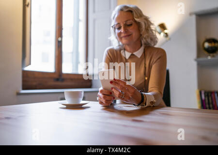 Coppia imprenditrice seduta a tavola con la tazza di caffè utilizza lo smartphone Foto Stock